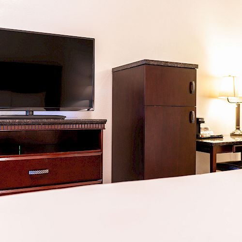 The image shows a hotel room with a TV, a cabinet, a desk, a lamp, and a chair in front of the desk, ending the sentence.