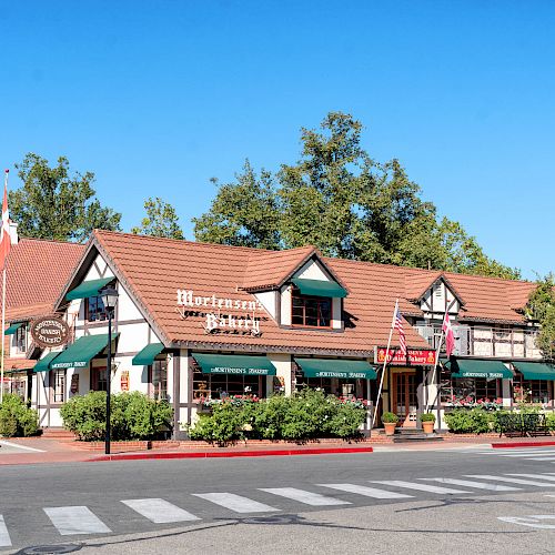 The image shows a charming building with a red roof and green awnings, housing a business named 